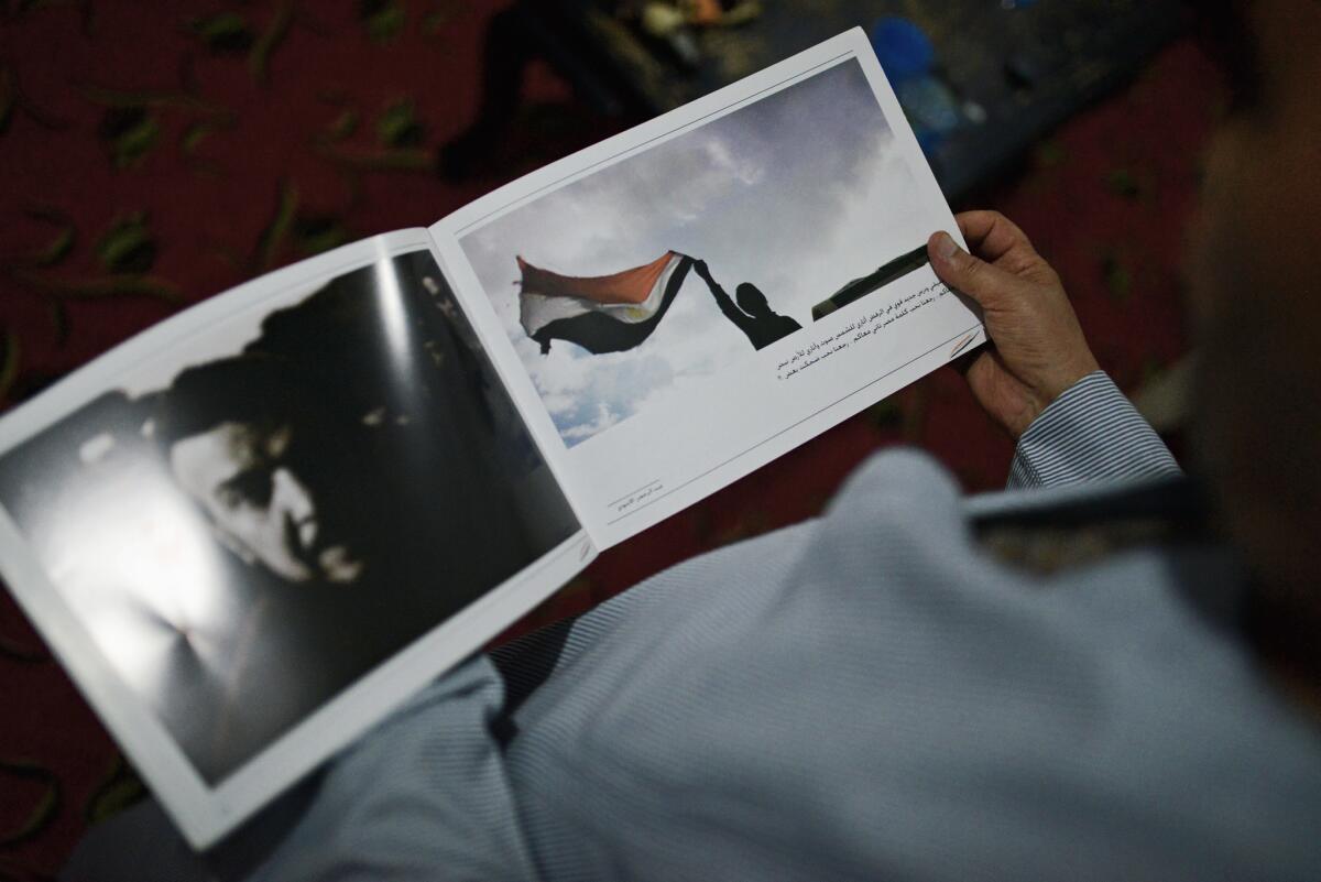 Abou Zeid's father holds a photo book that contains his son's documentation of the 2011 Egyptian revolution. J