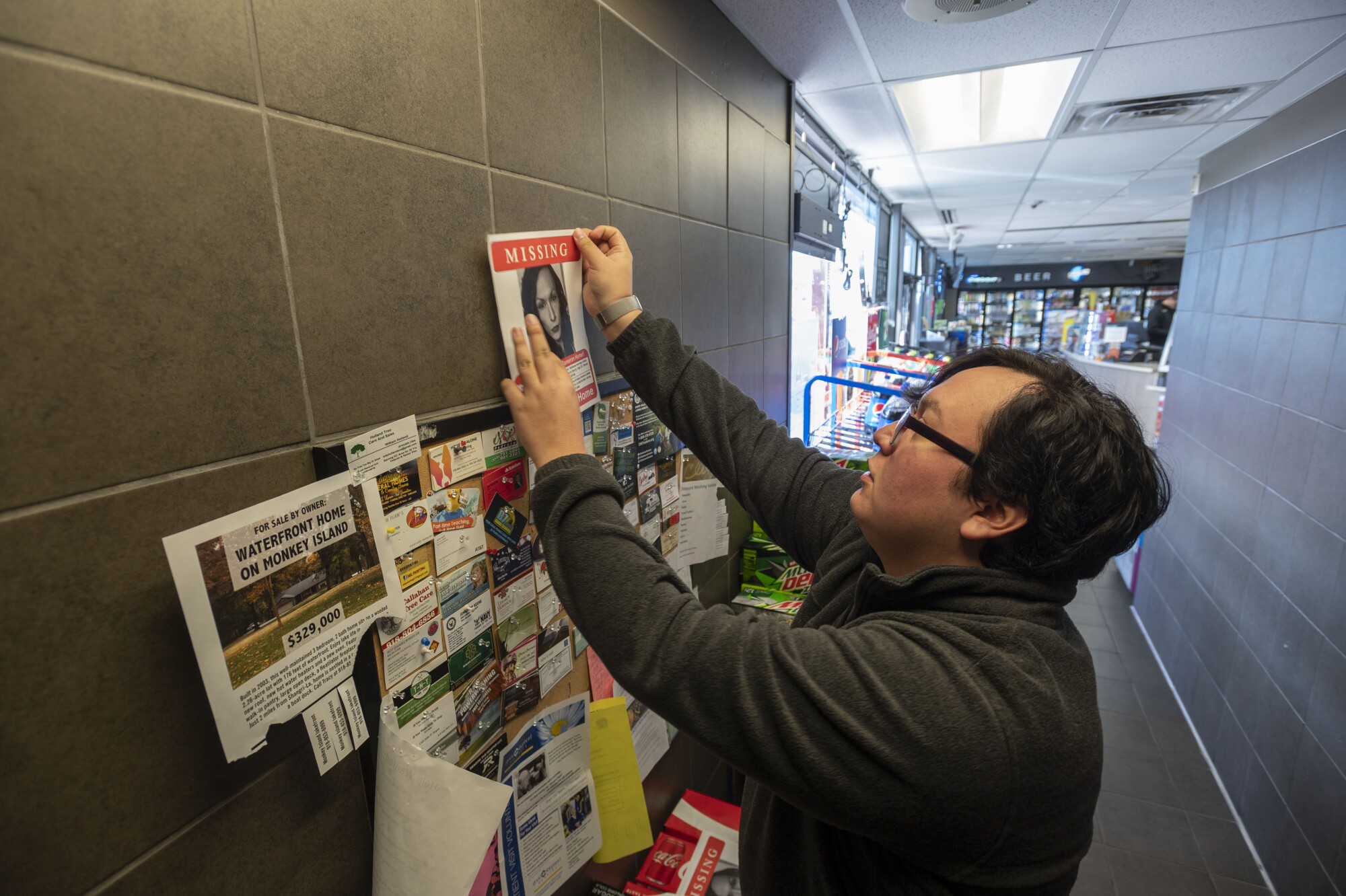 Fencer replaces a dated missing person poster of Dameron at a gas station in Grove.
