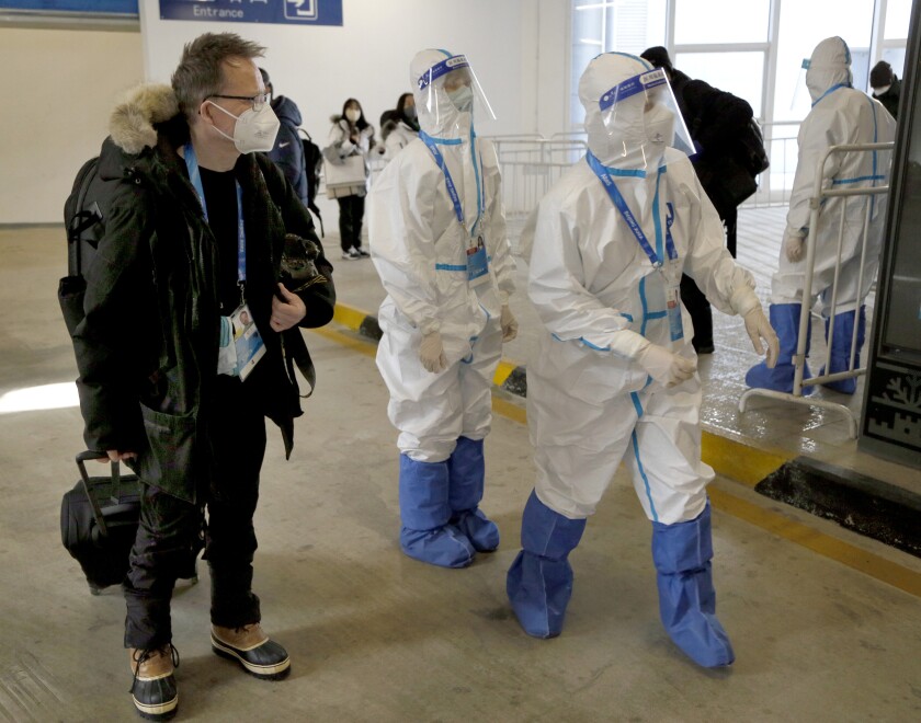 A journalist walks next to hazmat-clad transportation workers at the Taizicheng railway station.