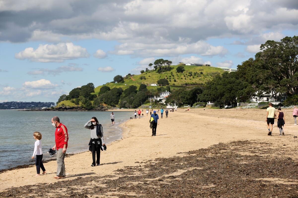 People walk on the beach in Auckland, New Zealand, Thursday, Sept. 2, 2021. The southern winter that just ended in New Zealand was the warmest ever recorded, and scientists say that climate change is driving temperatures ever higher. (Sylvie Whinray/New Zealand Herald via AP)