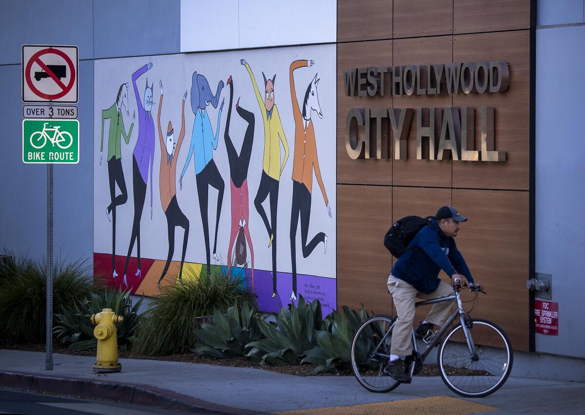 West Hollywood, CA - October 28: A person on a bike rides past the West Hollywood City Hall along Santa Monica Blvd. 
