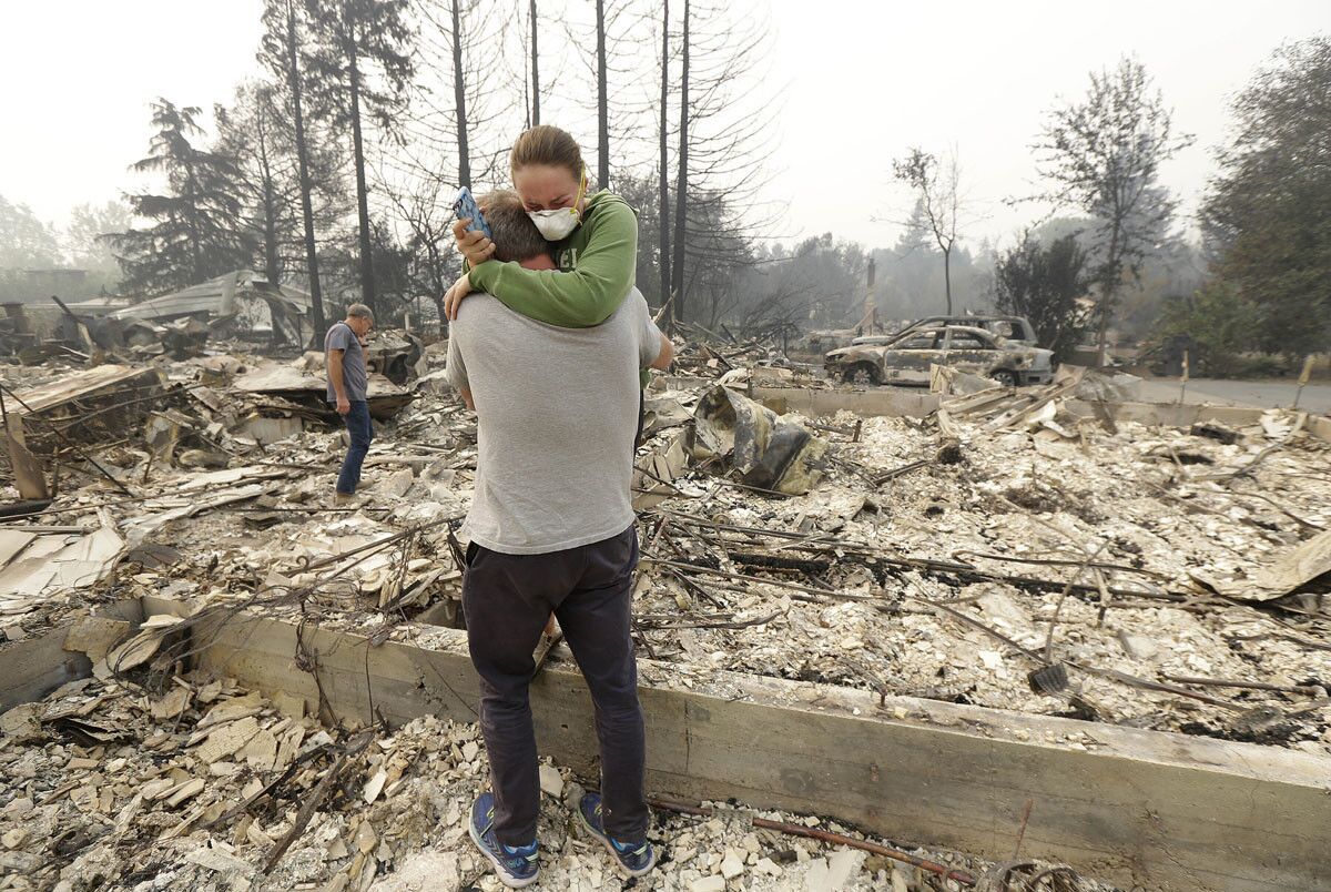 On Oct. 10, 2017, Todd Caughey hugs his daughter Ella as they visit the site of their home destroyed by fires in Kenwood, Calif. (Jeff Chiu/AP)