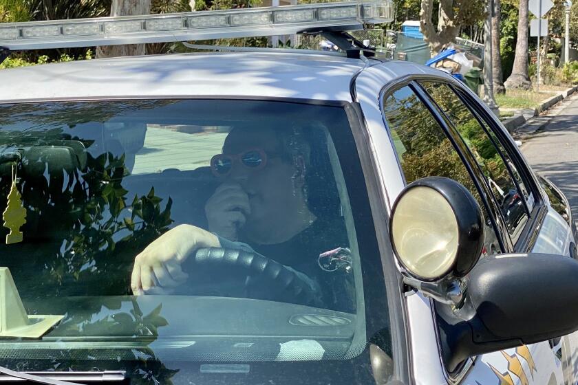 A man in  bright sunglasses driving a police car