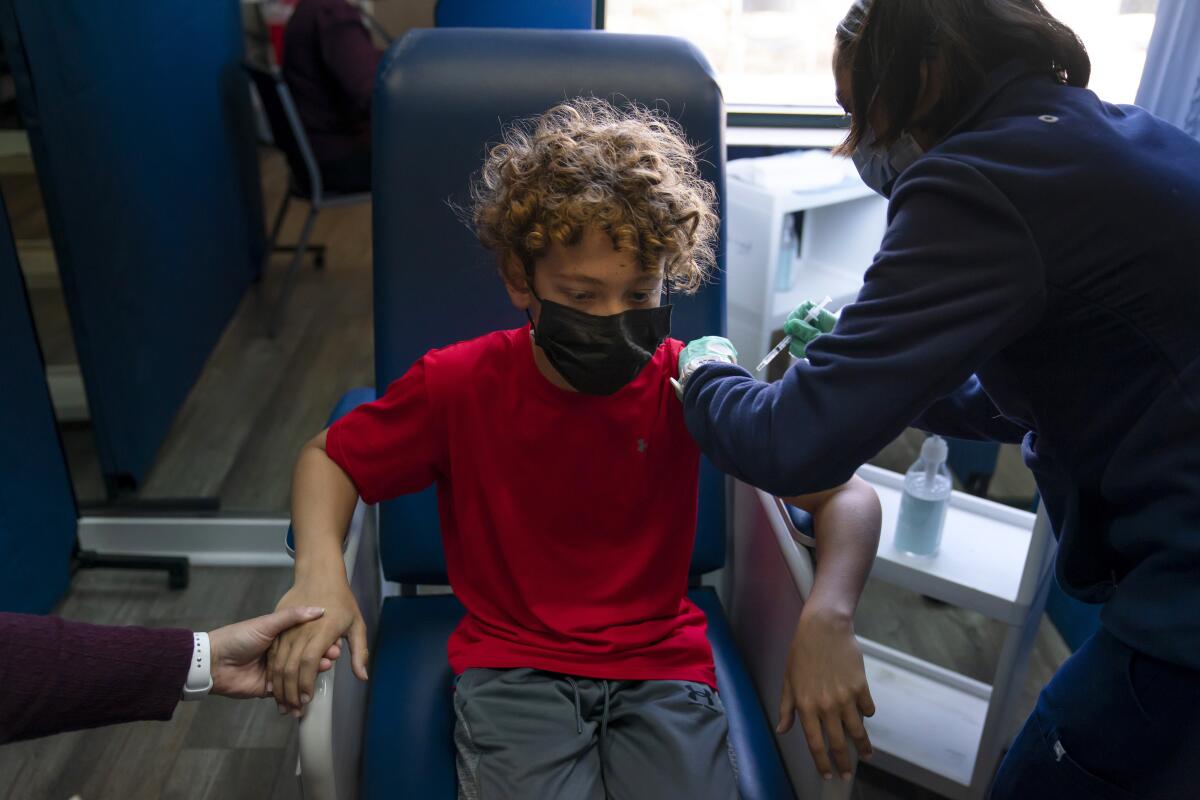 Max Cuevas, 12, holds his mother’s hand as he receives his first dose of a COVID-19 vaccine in Tustin in May.