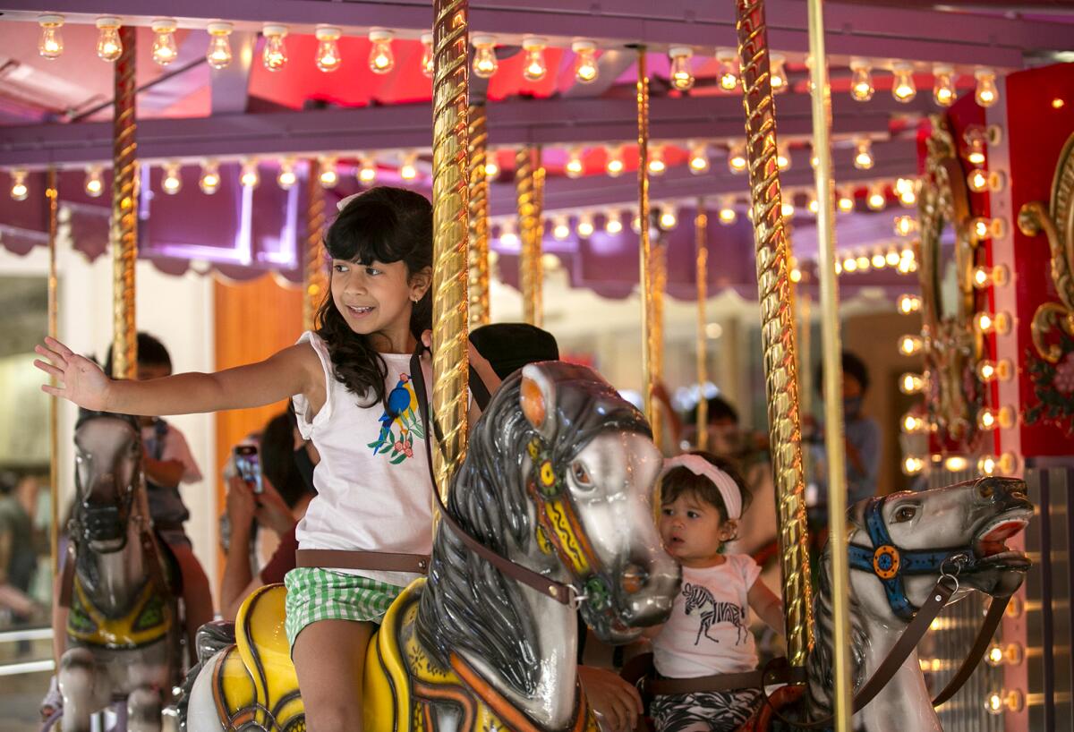 Catherynn Hoferitza, left, with mom Diana and sister Charlotte, ride the carousel at South Coast Plaza on Friday, June 25.