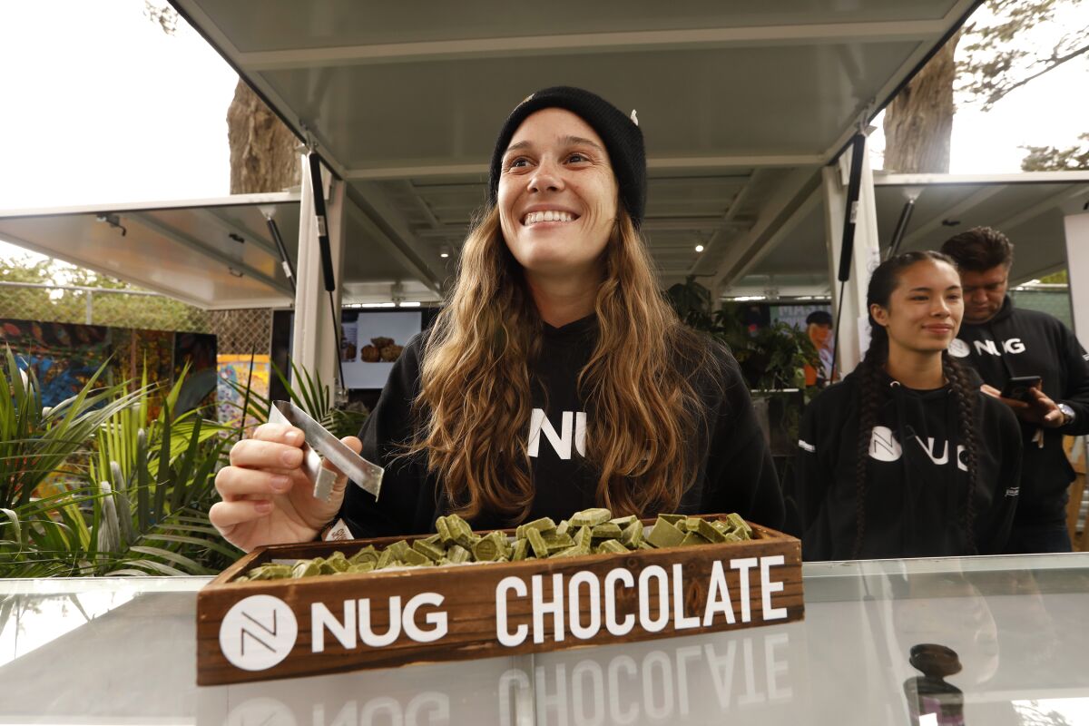 Kaydee Perreira at Grass Lands hands out non-laced squares of white chocolate mixed with matcha tea, a non-laced sample of candy bars sold by Nug, a dispensary with locations in Sacramento and Oakland.