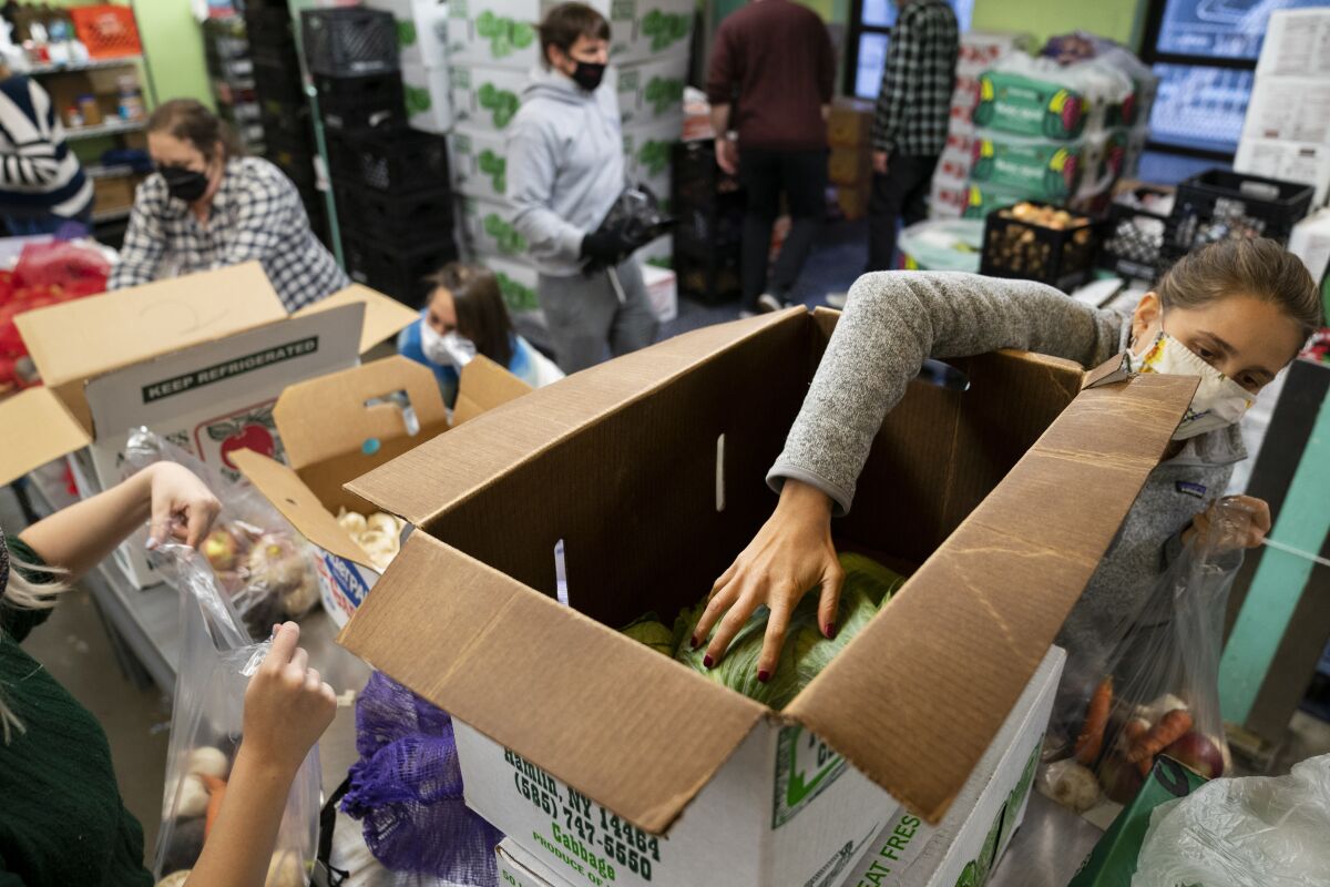 Volunteers package and distribute food for those in need at the New York Common Pantry on 109th Street, Wednesday, Dec. 1, 2021, in the Manhattan borough of New York. (AP Photo/John Minchillo)