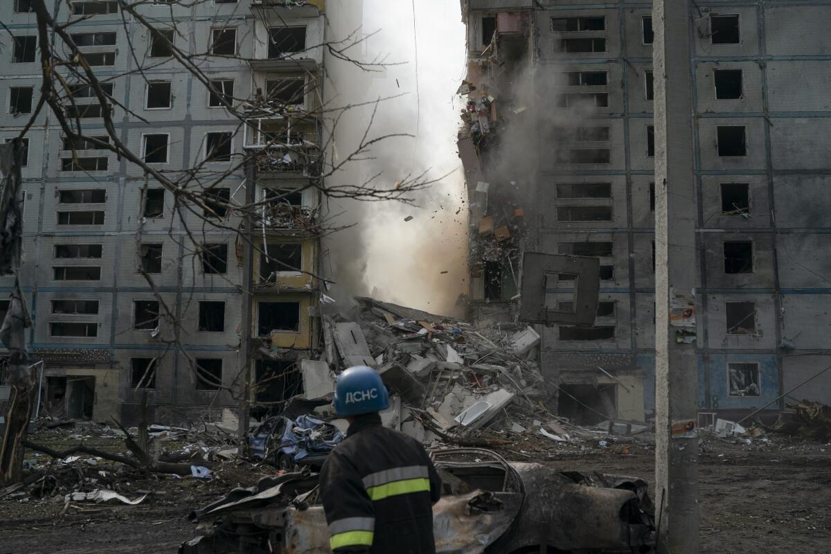 A firefighter watches a wall crumble from a damaged building in Ukraine.
