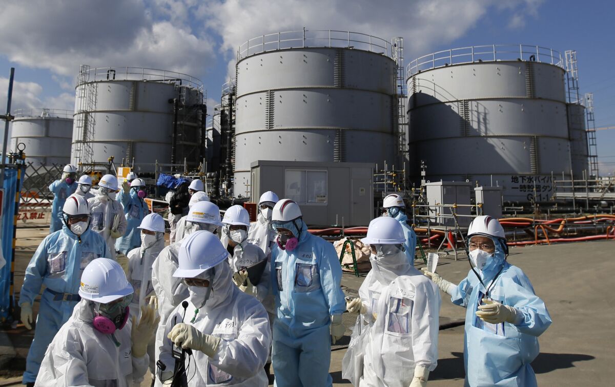 A media tour group in protective suits stands near the tsunami-crippled Fukushima Daiichi nuclear power plant in Okuma, Japan, on Feb. 10, 2016.