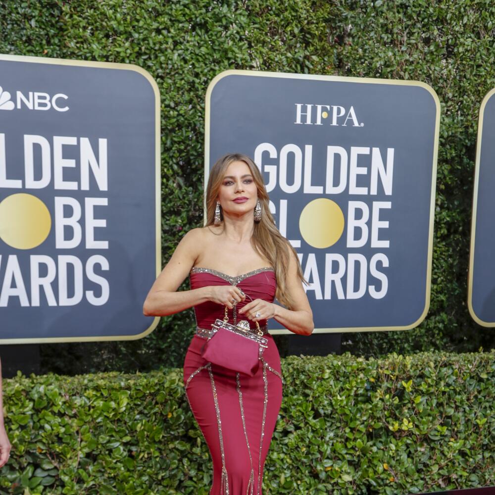 Sofia Vergara, in a form-fitting red dress, holds a red purse on the red carpet of the Golden Globe Awards in 2020.