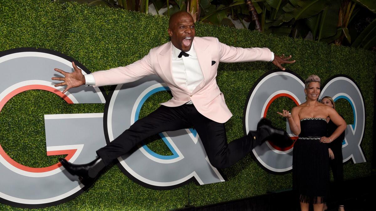 Terry Crews jumps at the GQ Men of the Year party as his wife, Rebecca King-Crews, watches.