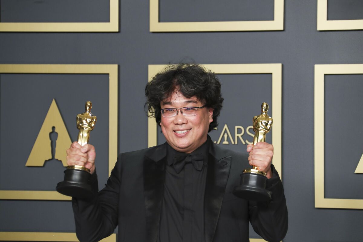 Director Bong Joon Ho holding two Oscar trophies