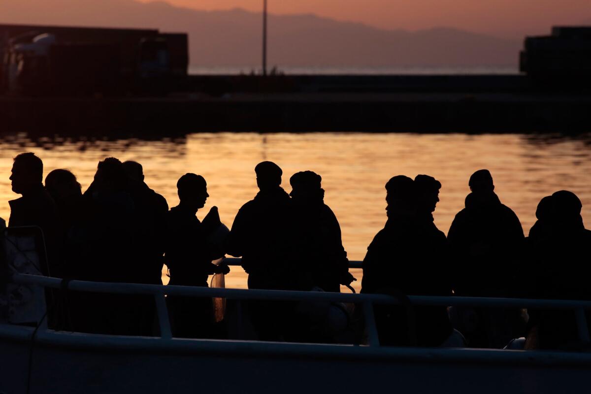 Police escort migrants, who are being deported from Lesbos, Greece, onto a ferry bound for Turkey.