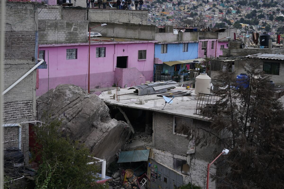 A boulder that plunged from a mountainside rests among homes in Tlalnepantla, on the outskirts of Mexico City, when a mountain gave way on Friday, Sept. 10, 2021. A section of mountain on the outskirts of Mexico City gave way Friday, plunging rocks the size of small homes onto a densely populated neighborhood and leaving at least one person dead and 10 others missing. (AP Photo/Eduardo Verdugo)