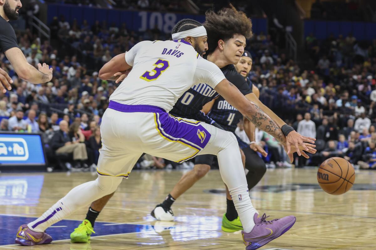 Lakers forward Anthony Davis (3) reaches with his right hand to try to grab the basketball from Magic guard Anthony Black.