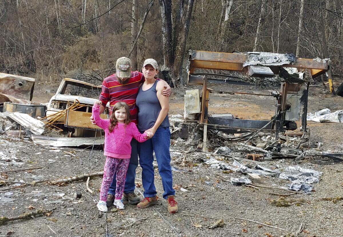 Tye and Melynda Small standing with their 5-year-old daughter, Madalyn, amid the ruins of their home in Otis, Oregon