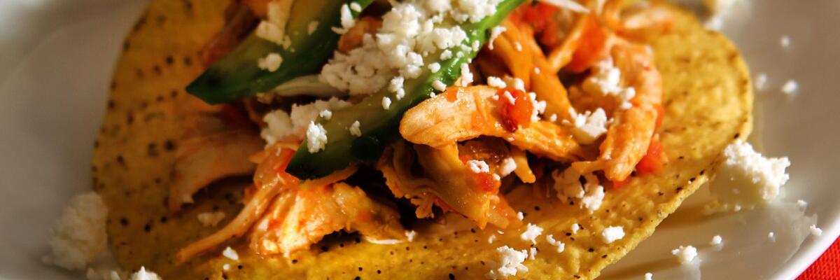 Cheese is sprinkled on Tinga de Pollo.