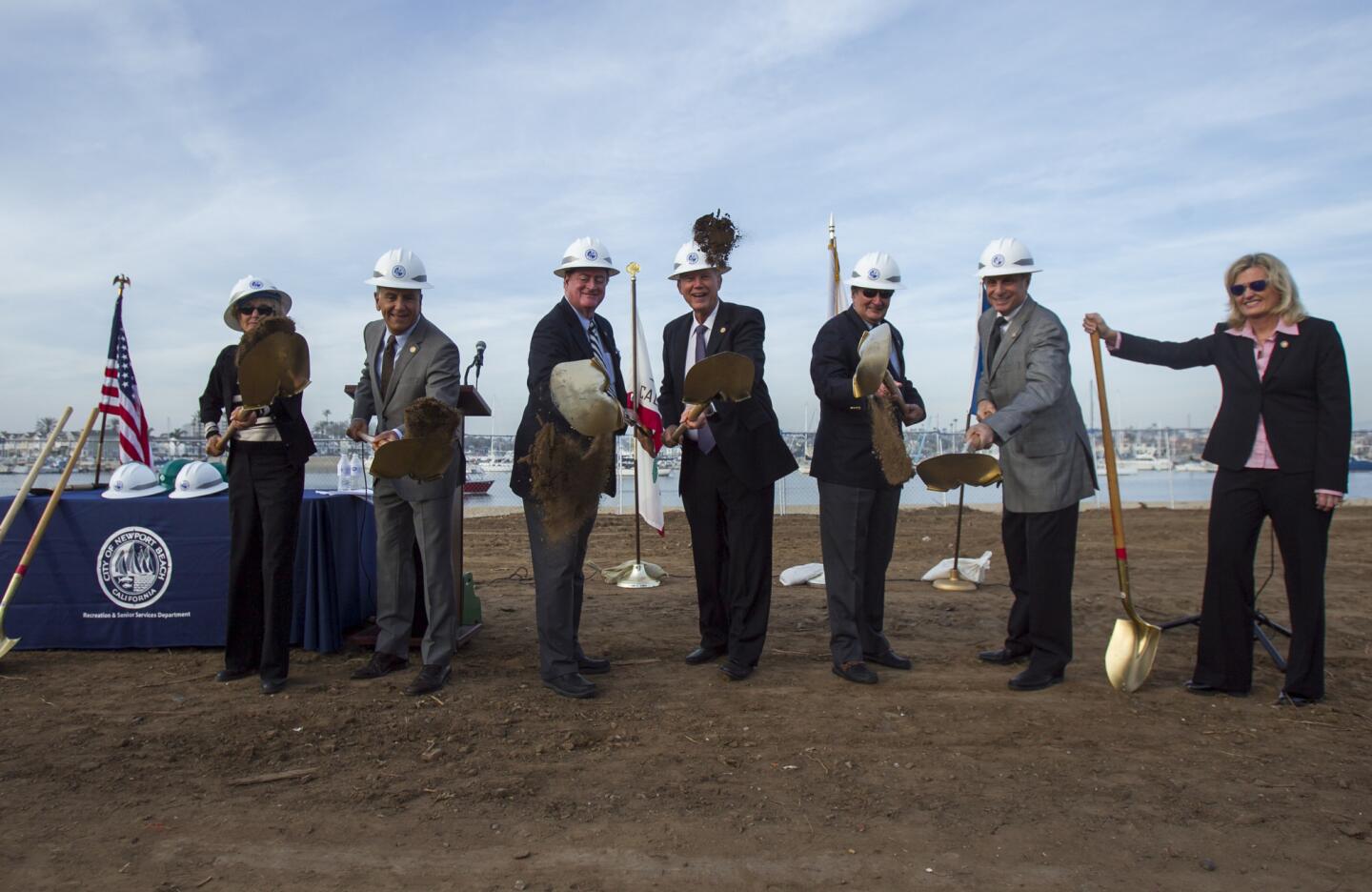 Members of the Newport Beach City Council Nancy Gardner, left, Tony Petros, Keith Curry, Mayor Rush Hill, Mayor Pro Tem Edward Selich, Michael Henn and Leslie Daigle toss a ceremonial shovel of dirt during the groundbreaking ceremony for Marina Park on Balboa Peninsula on Tuesday, February 11.