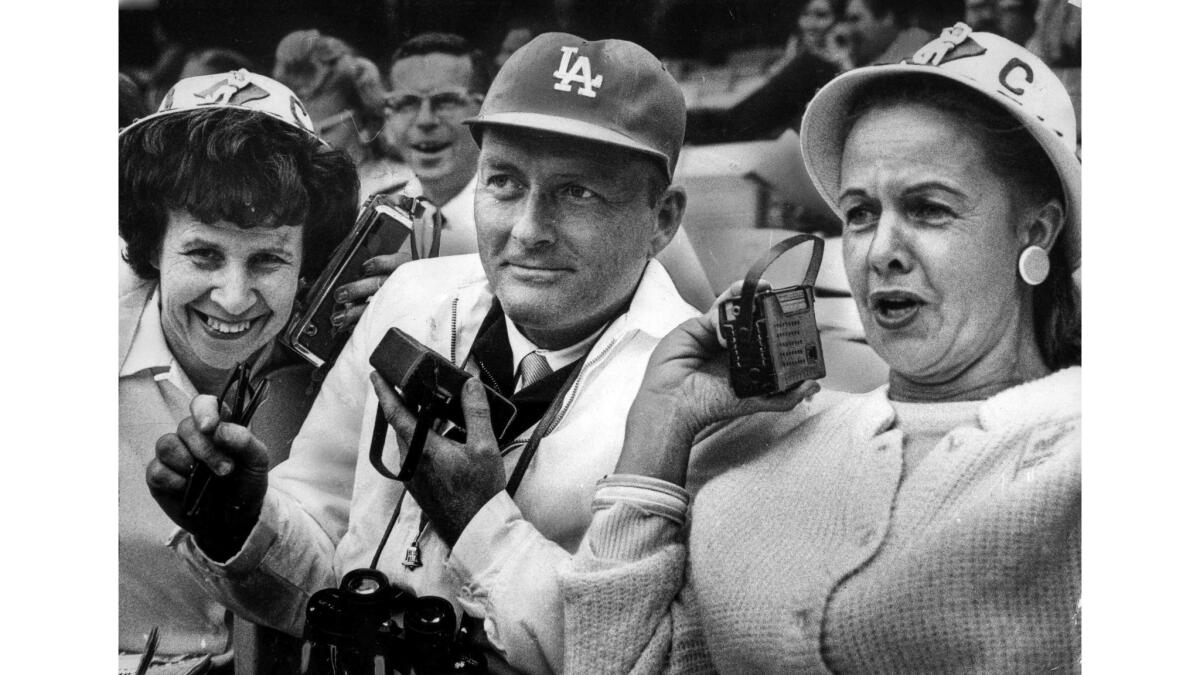 June 2, 1965: Dodgers Booster club members Gladys Fuqua, left, Rolfe Larsen, center, and Vangie Scoler listen to Vin Scully.