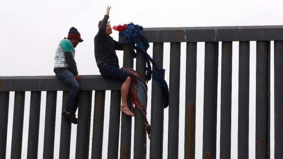 TIJUANA, March 21, 2019 | Minutes before he drops down on the U.S. side of the U.S. - Mexican border barrier, with Border Patrol agents waiting, a Honduran migrant raises up his arm at Playas de Tijuana, Mexico on Thursday. | Photo by Hayne Palmour IV/San Diego