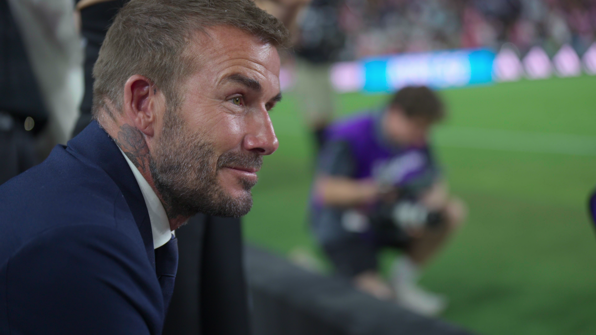 A close-up of David Beckham on the sidelines of a football pitch