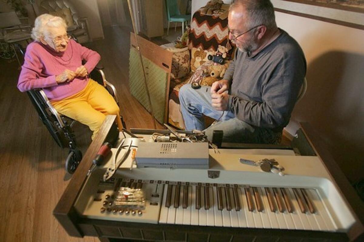 FIXING THINGS: Michael Tomazin does repairs on Helen Jones organ, which hasnt worked for years, at her home in Yucaipa.