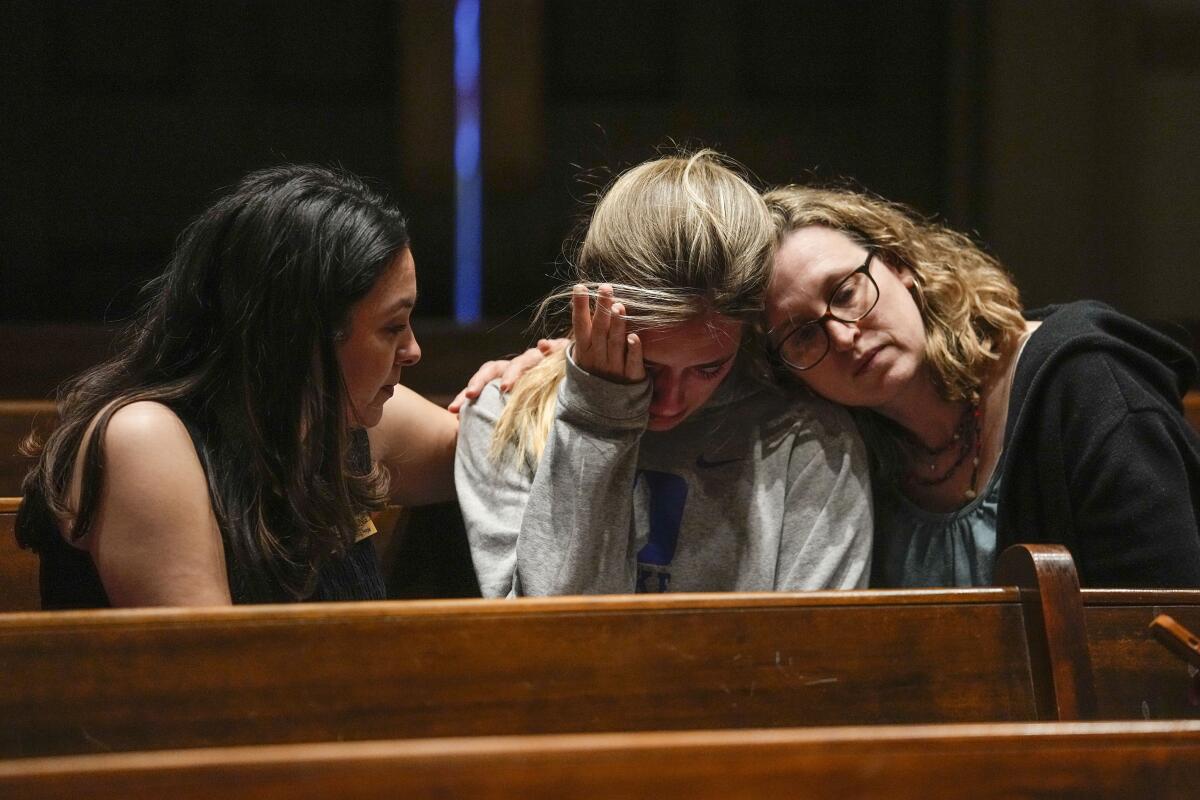 Three women huddled in a church pew