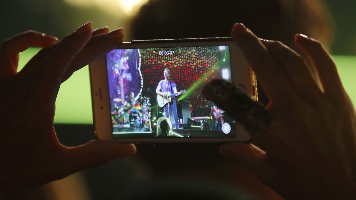 A fan records Coldplay as they perform during their A Head Full of Dreams Tour at SDCCU Stadium in San Diego on Oct. 8, 2017. (Photo by K.C. Alfred/The San Diego Union-Tribune)