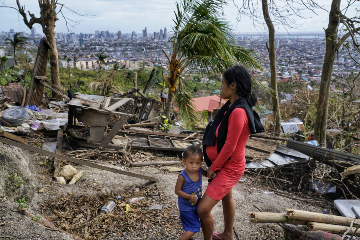 Alona Nacua and her son look over their demolished home in the Philippines’ Cebu province on Christmas Day.