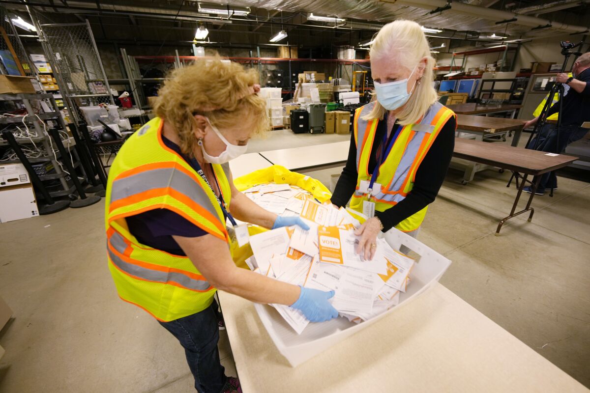 Election judges Violet Wellborn, left, and Valerie Hayes-Aneage process early ballots in the Jefferson County elections division, Tuesday, Oct. 26, 2021, in Golden, Colo. Officials were highlighting the steps taken to ensure that the election is carried out seamlessly. (AP Photo/David Zalubowski)