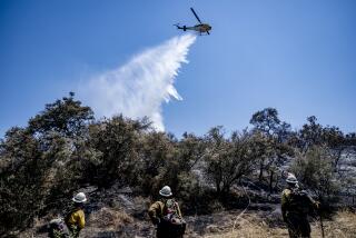 BEAUMONT, CA - JULY 16, 2023: Fire crews get help from a water dropping helicopter while putting out hotspots near Bolo Court at the Rabbit fire on July 16, 2023 in Beaumont, CA. (Gina Ferazzi / Los Angeles Times)