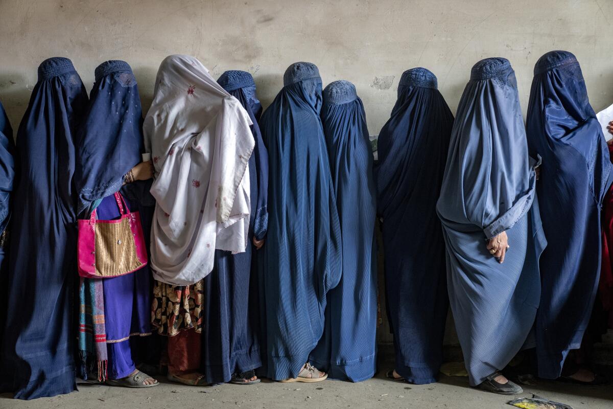 Mujeres afganas esperan recibir raciones de alimentos distribuidas por un grupo de ayuda humanitaria, 