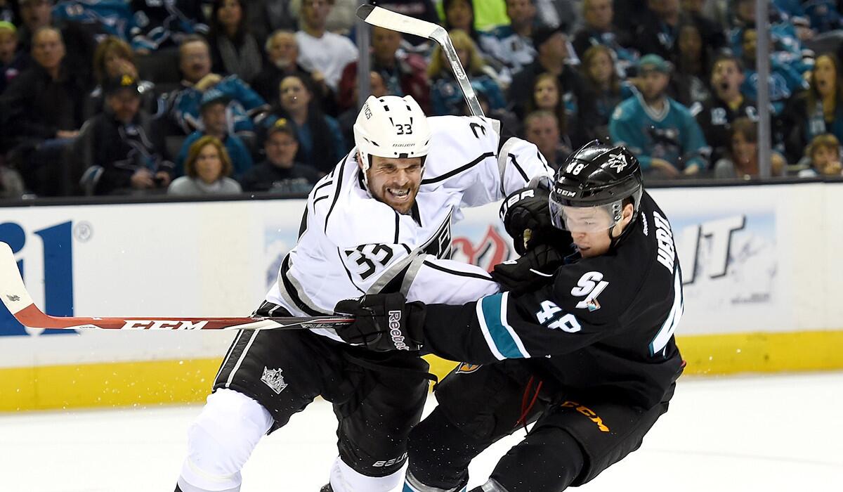 Kings defenseman Willie Mitchell (33) collides with Sharks center Tomas Hertl as he shoots during Game 5 of their playoff series. Mitchell didn't join his teammates for Game 1 against the Ducks on Saturday.