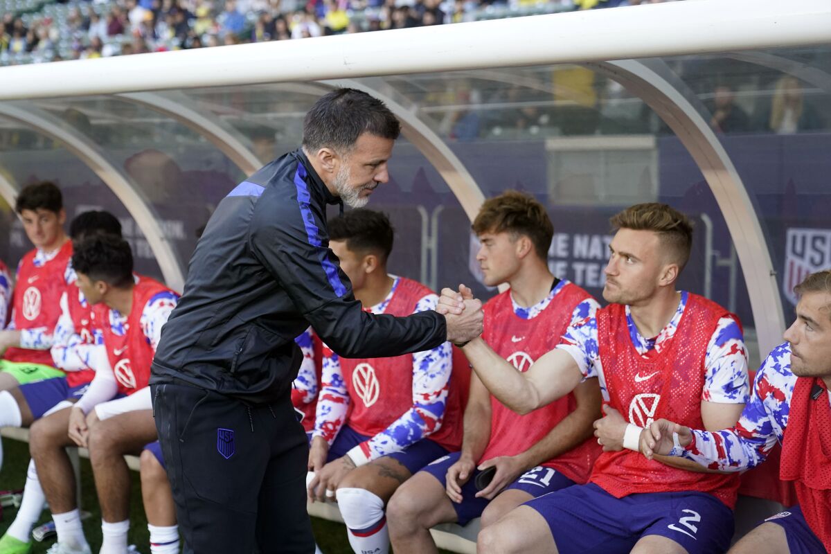 L'entraîneur américain Anthony Hudson serre la main des joueurs sur le banc avant un match amical international.