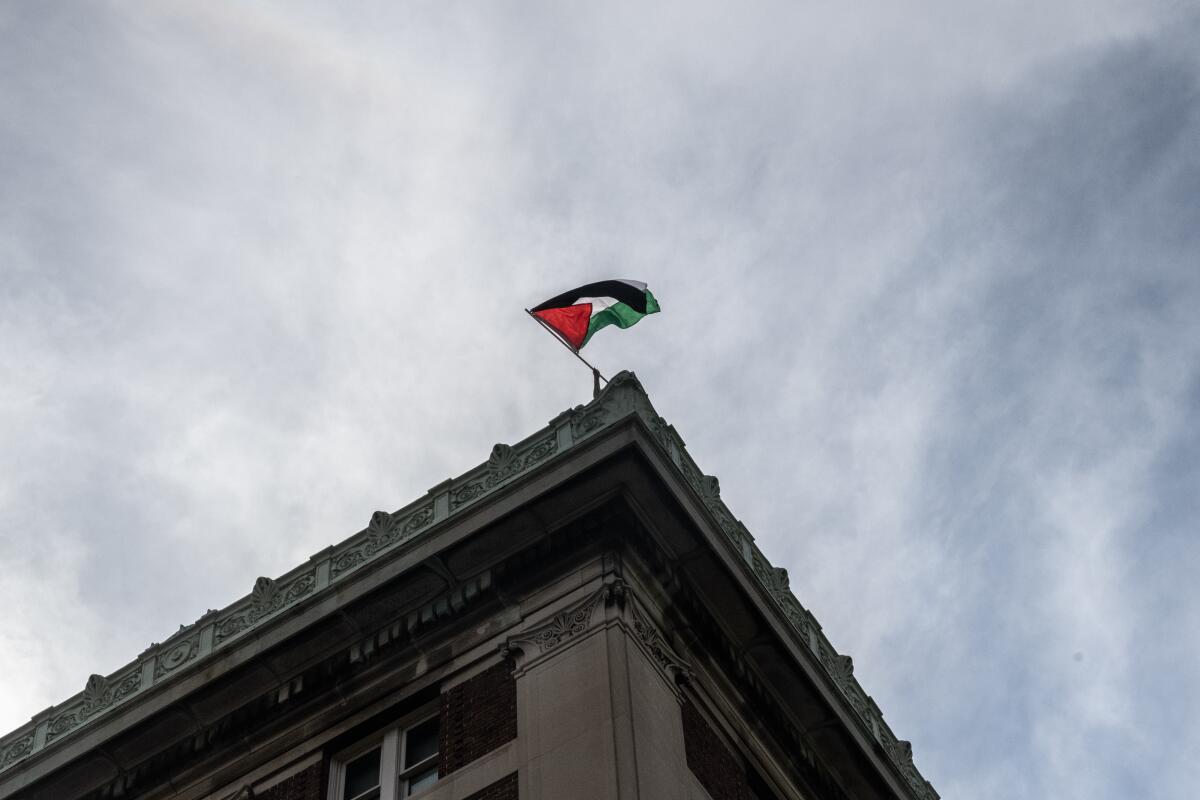 A Palestinian flag flies above the corner of a building.
