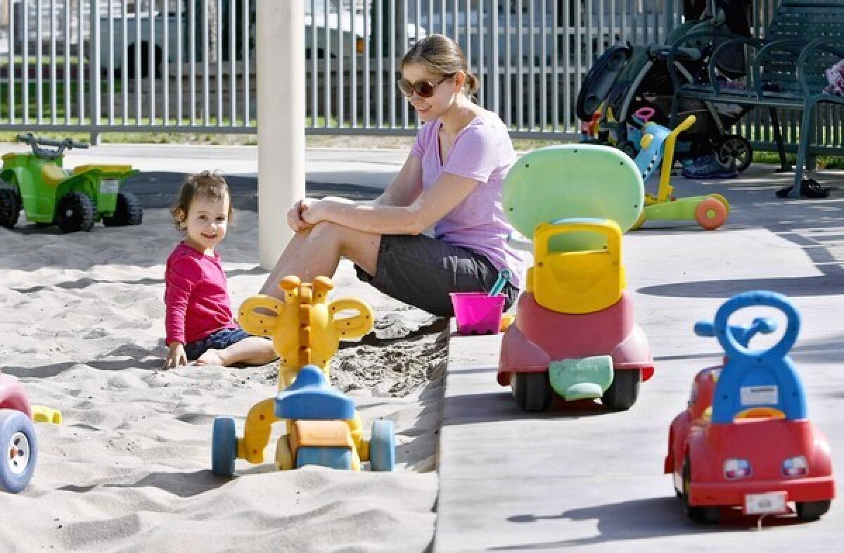 Jennifer Allen, 34 of Burbank, and her daughter Lucy, 22 months, are surrounded by toys left behind by others at Lincoln Park in Burbank on Tuesday, August 13, 2013. Children use the toys when they come to play in this fenced in area of the park. The city plans to remove all the toys without owners by August 21 because of safety concerns.