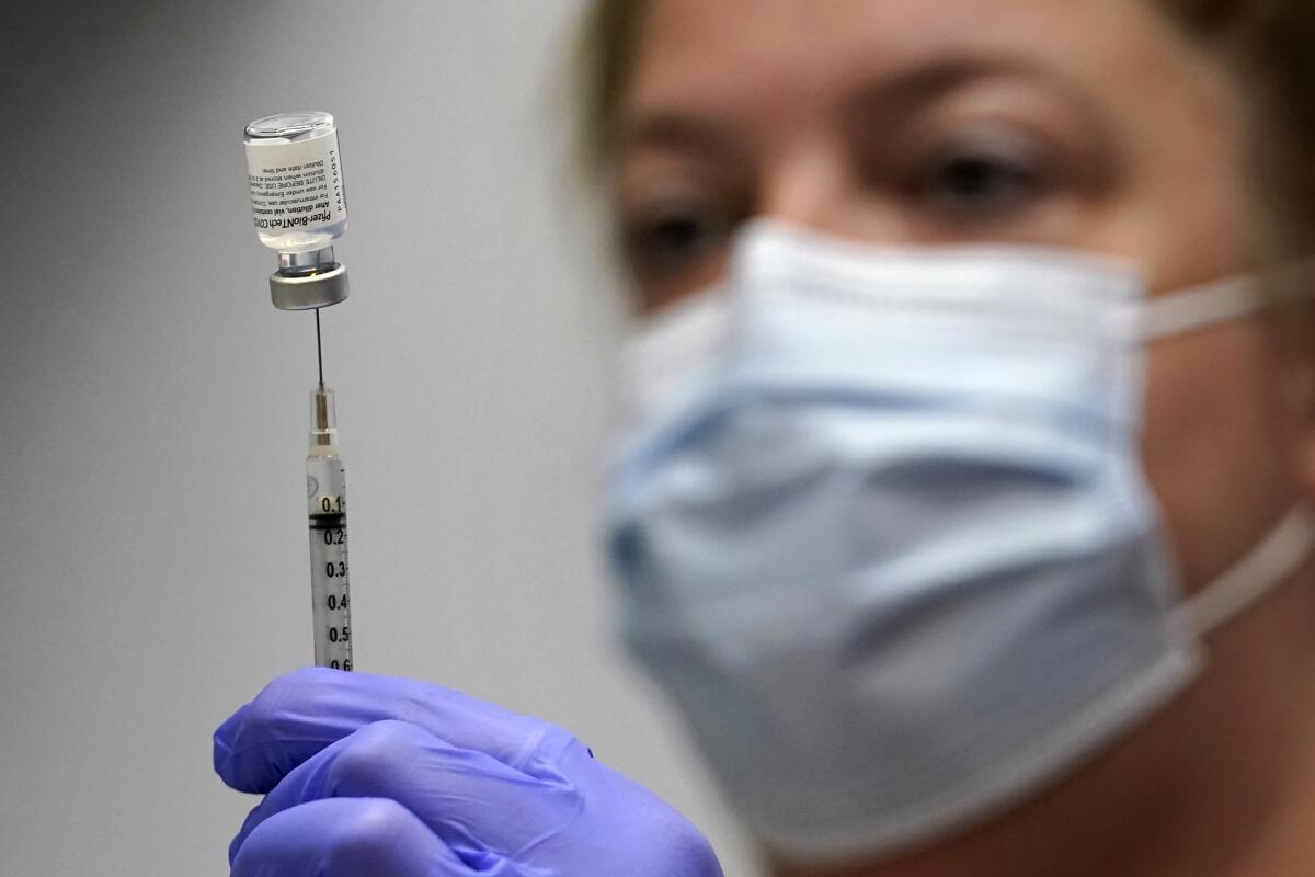 La técnica de laboratorio Hollie Maloney carga una jeringa con la vacuna de Pfizer contra el COVID-19