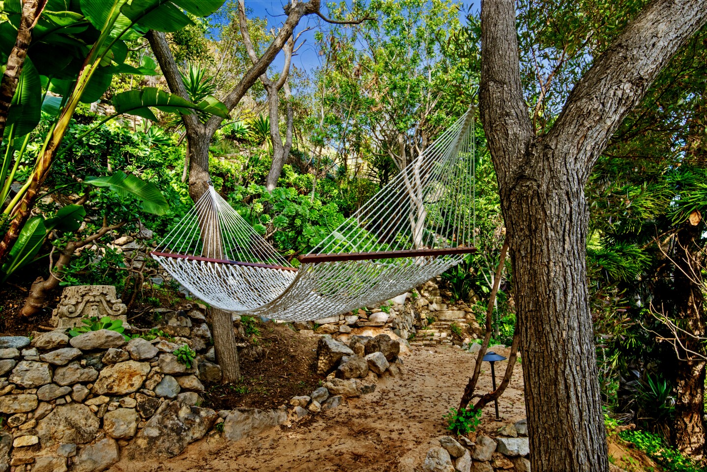 The contemporary-style home, developed by former Hollywood duo Janus Cercone and Michael Manheim, sits on a lush, one-acre lot in Malibu with 270-degree ocean views. Tropical landscaping creates a backdrop for an adult treehouse, hidden pathways and a hammock installed between two trees. There's also a 12-person spa and an infinity-edge pool that can be controlled by a smartphone. Listed for $11.45 million, the single-story house was redesigned so that all but one room takes in a view of the ocean, while skylights were added to bathe the interior in natural light. Among features is a custom Moroccan amethyst geode sink in the powder room. The unique sink fixture is fed by a ceiling faucet.