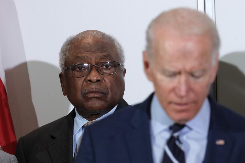 In this Feb. 26, 2020 photo, House Majority Whip, Rep. Jim Clyburn, D-S.C., background, listens as Democratic presidential candidate former Vice President Joe Biden, speaks at an event where Clyburn endorsed him in North Charleston, S.C. (AP Photo/Gerald Herbert)