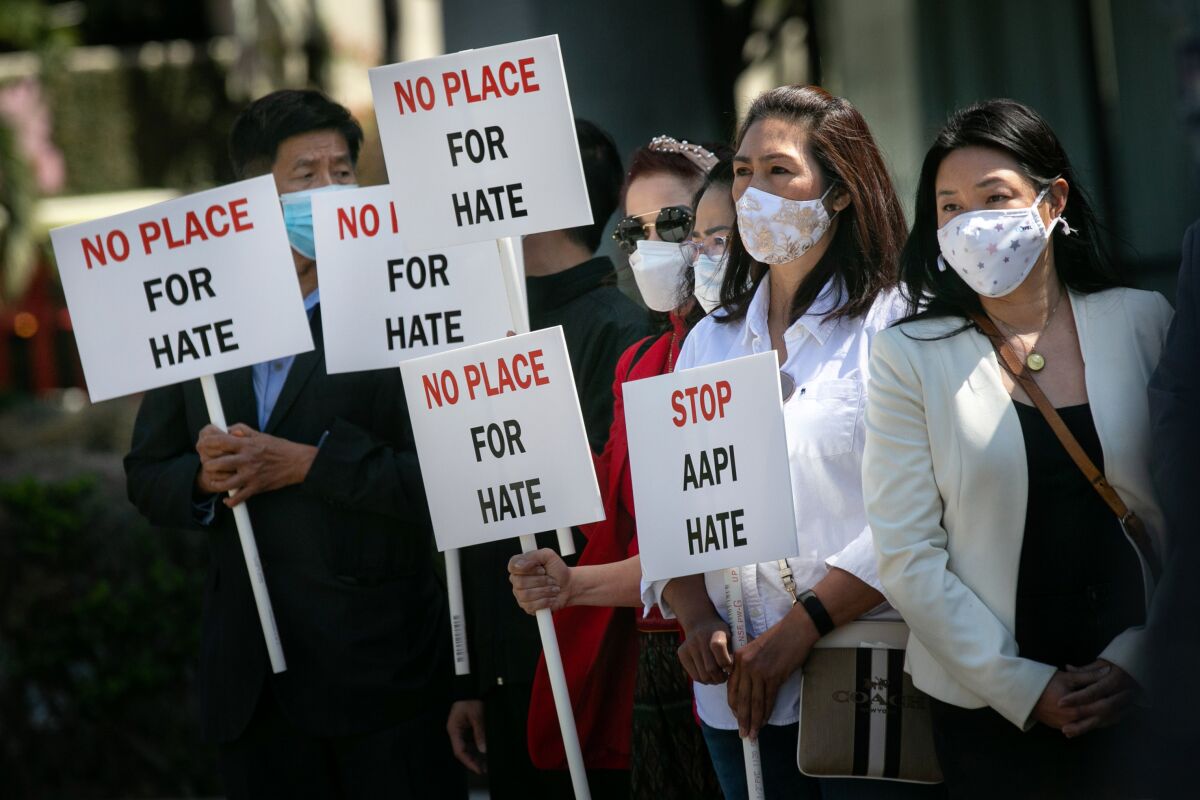 Asian community members hold signs against hate at a news conference in Los Angeles on Monday.  