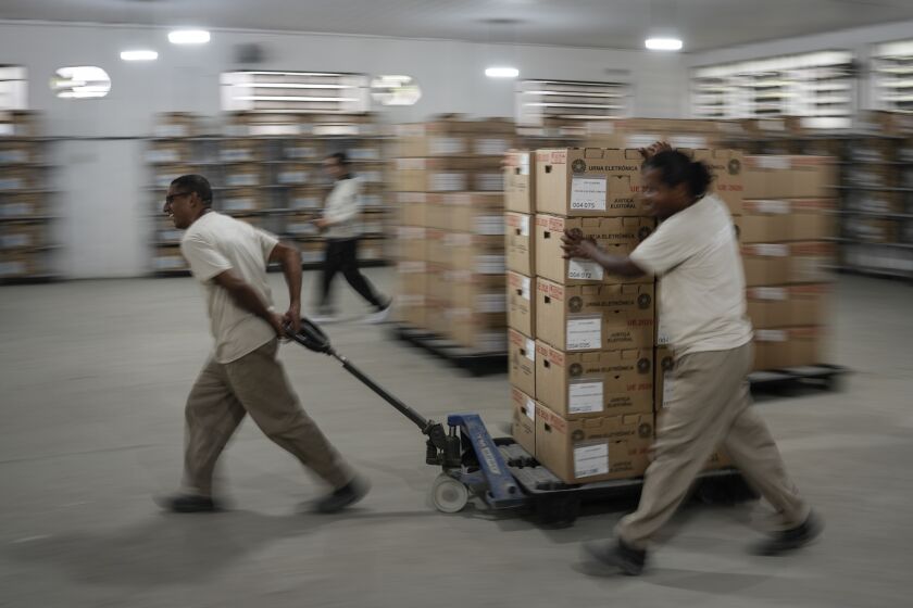 Electoral workers move electronic voting machine boxes at a distribution center in Rio de Janeiro, Brazil, Saturday, Oct. 1, 2022. Brazil's general elections are scheduled for Oct. 2. Brazilians head to polls on Oct. 2 to elect a president, vice president, governors and senators. (AP Photo/Matias Delacroix)