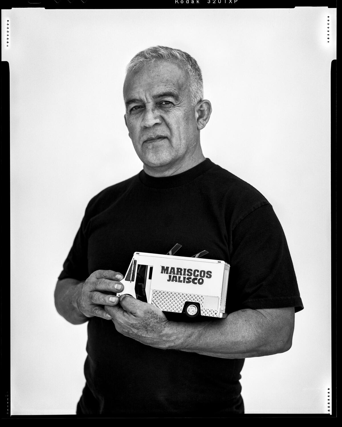 Black and white film photo of a man, Raul Ortega, holding a model Mariscos Jalisco food truck