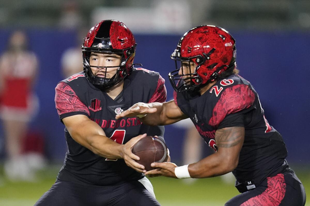 San Diego State quarterback Jordon Brookshire hands off to running back Kaegun Williams during game against New Mexico.