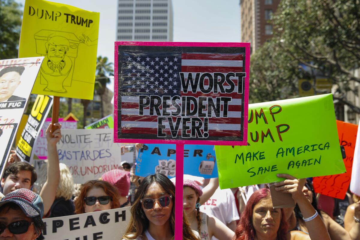 A variety of anti-Trump signs are displayed in Pershing Square before the start of the impeachment march in downtown L.A. in July.