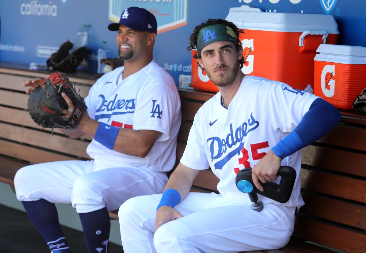 Dodgers first baseman Albert Pujols, left, and center fielder Cody Bellinger sit in the dugout.