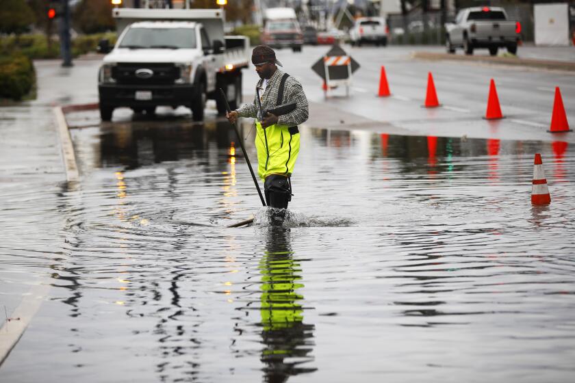 Douglas Owens, with the City of San Diego, monitors an area that flooded along Harbor Blvd. in downtown San Diego on Dec. 23, 2019. The area backs up with water when it rains and there is a high tide.