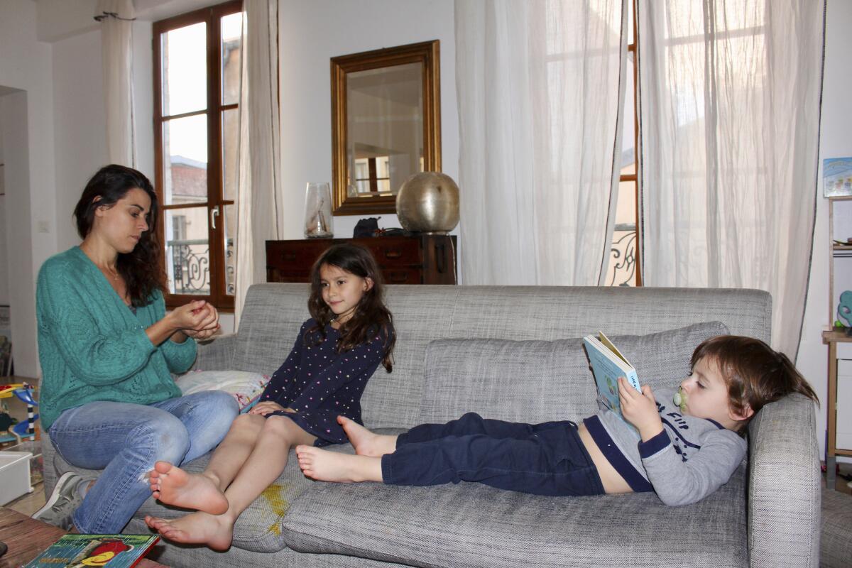Mathilde Manaud plays on a sofa with her children Mila, 7, and Andre, 3, in Paris on April 30. Many French parents are deeply torn over whether to send their children to school when they reopen starting Monday.