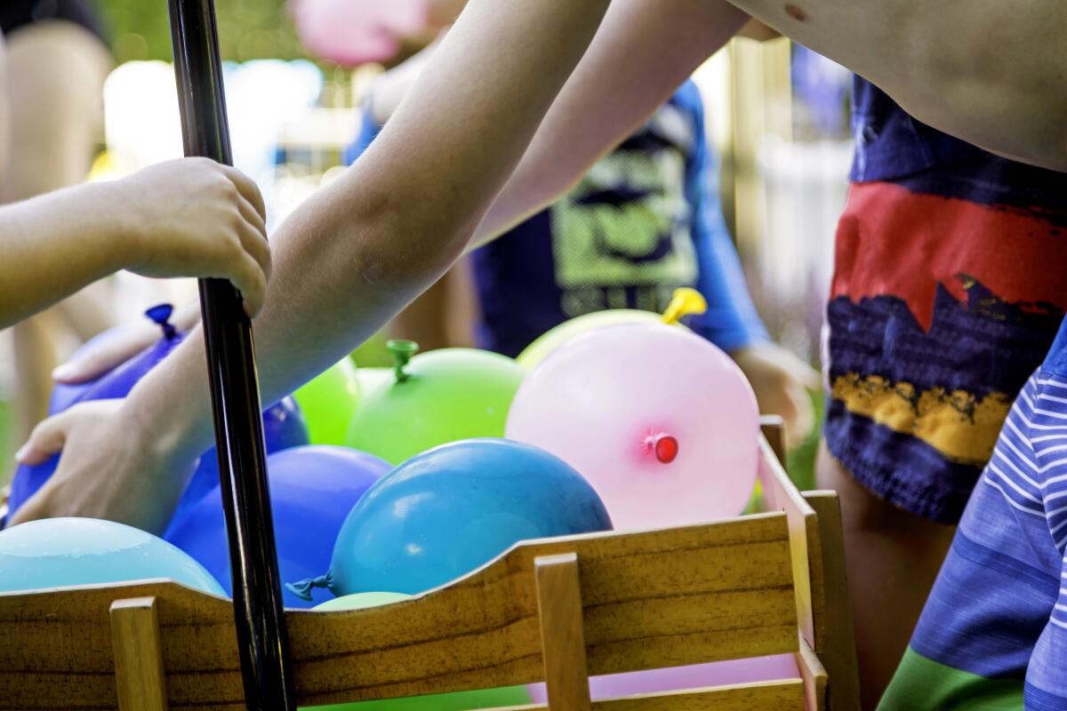 Kids reach for water balloons in a wagon. 