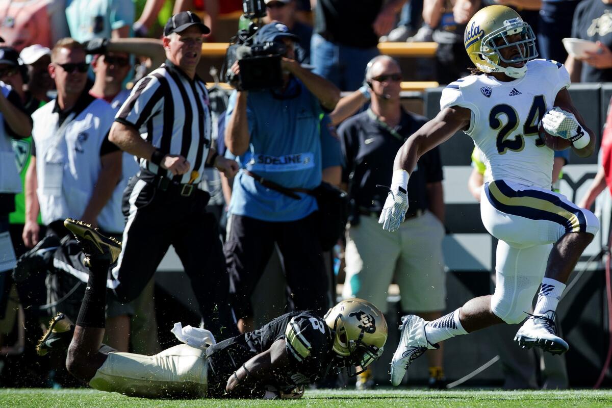 UCLA running back Paul Perkins, right, escapes a tackle attempt by Colorado cornerback Kenneth Crawley to score a first-quarter touchdown on Oct. 25. The Bruins beat the Buffaloes, 40-37, in double overtime.