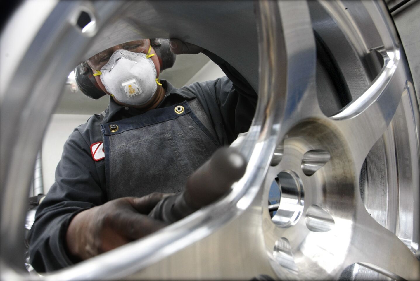 A worker polishes a solid aluminum wheel at HRE Performance Wheels.